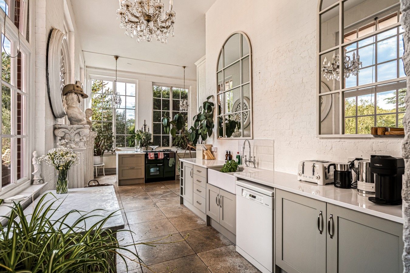 A spacious kitchen with a central island, large windows, and a chandelier.