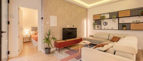 Una sala moderna con un sofá, televisor y una pequeña mesa de centro.