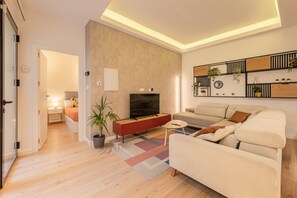 A modern living room with a sofa, TV, and a small coffee table. - ‘Almaroma Central’ Apartment with Private Terrace, Wi-Fi & Air Conditioning (Seville)