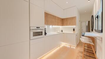 Una cocina moderna con armarios blancos, encimera de madera y horno empotrado.