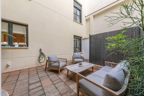 A patio with a wooden table and two chairs, a small potted plant, and a window with a view of the sky. - ‘Almaroma Central’ Apartment with Private Terrace, Wi-Fi & Air Conditioning (Seville)
