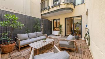 Un patio con sofá, sillas, una mesa baja y plantas en macetas.