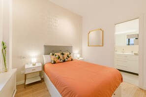 A bedroom with a bed, nightstands, a bedside lamp, a mirror, and a bathroom with a sink and mirror. - ‘Almaroma Central’ Apartment with Private Terrace, Wi-Fi & Air Conditioning (Seville)