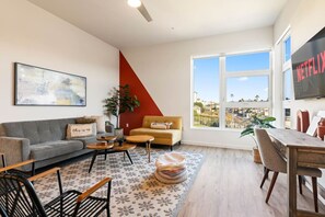 A modern living room with a sofa, coffee table, and a dining area with chairs. - Private Skyloft W/ DTLA Views - 1Mi to  Dodger Std (Los Angeles)