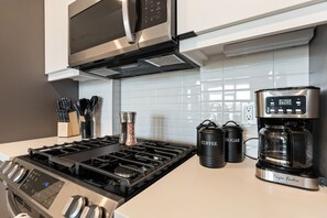 A modern kitchen with a gas stove, a coffee maker, and two containers labeled 'Coffee' and 'Sugar'. - Private Skyloft W/ DTLA Views - 1Mi to  Dodger Std (Los Angeles)
