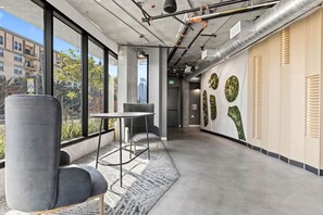 Ein moderner Arbeitsraum mit großem Fenster, einem Tisch, zwei Stühlen und einer Wand mit Grünpflanzen.