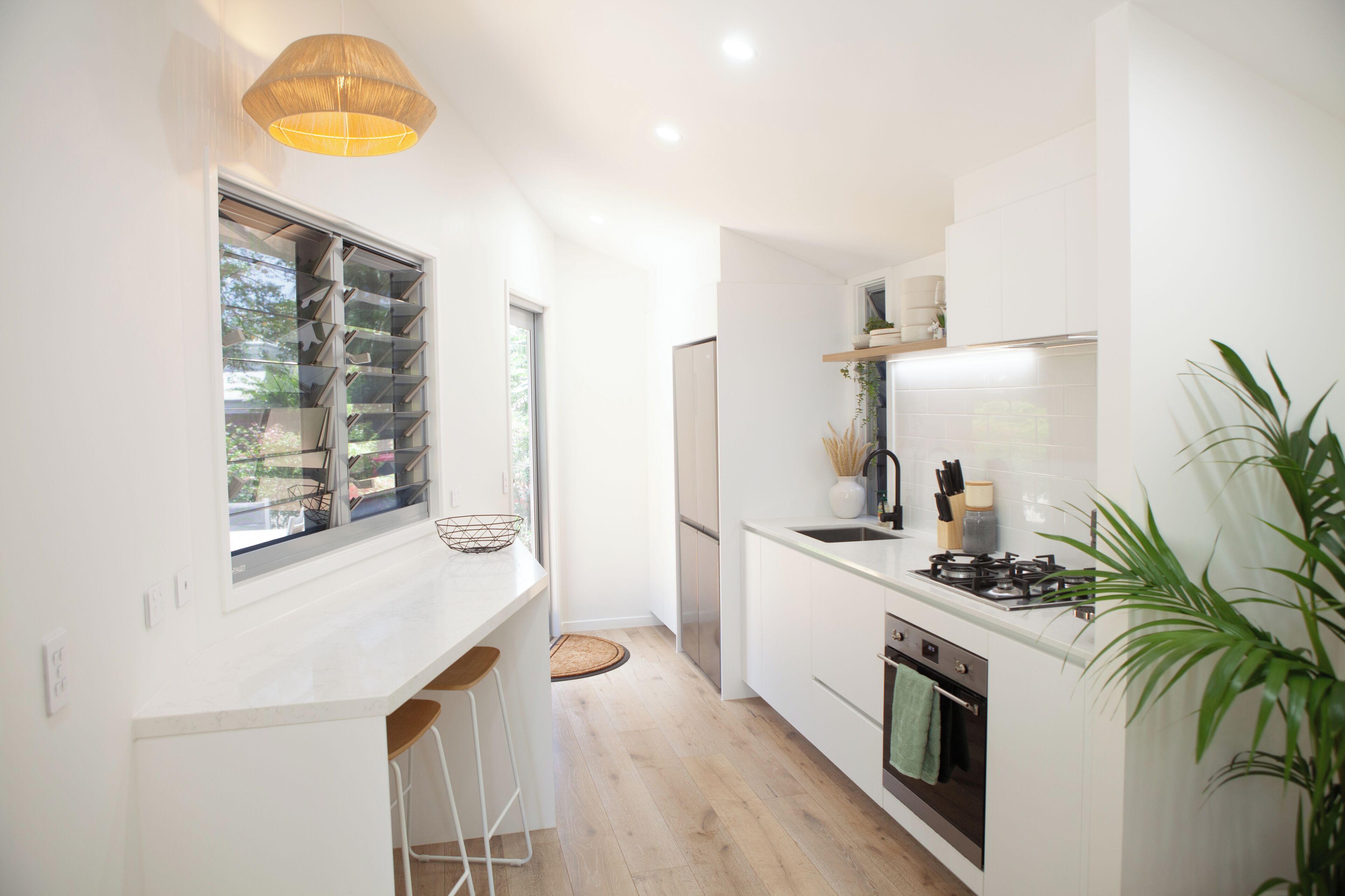 Una cocina moderna con ventana, taburetes de bar, estufa y lavaplatos.