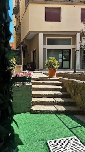 A building with a set of stone steps leading to a door, a potted plant on the steps, and a green artificial turf area. - Stella Marina. Your getaway just a stone's throw from the sea, Ligurian villages, and the French Riviera. (Bordighera)