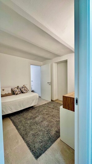 A bedroom with a bed, a bedside table, a nightstand, and a door leading to another room. - Stella Marina. Your getaway just a stone's throw from the sea, Ligurian villages, and the French Riviera. (Bordighera)