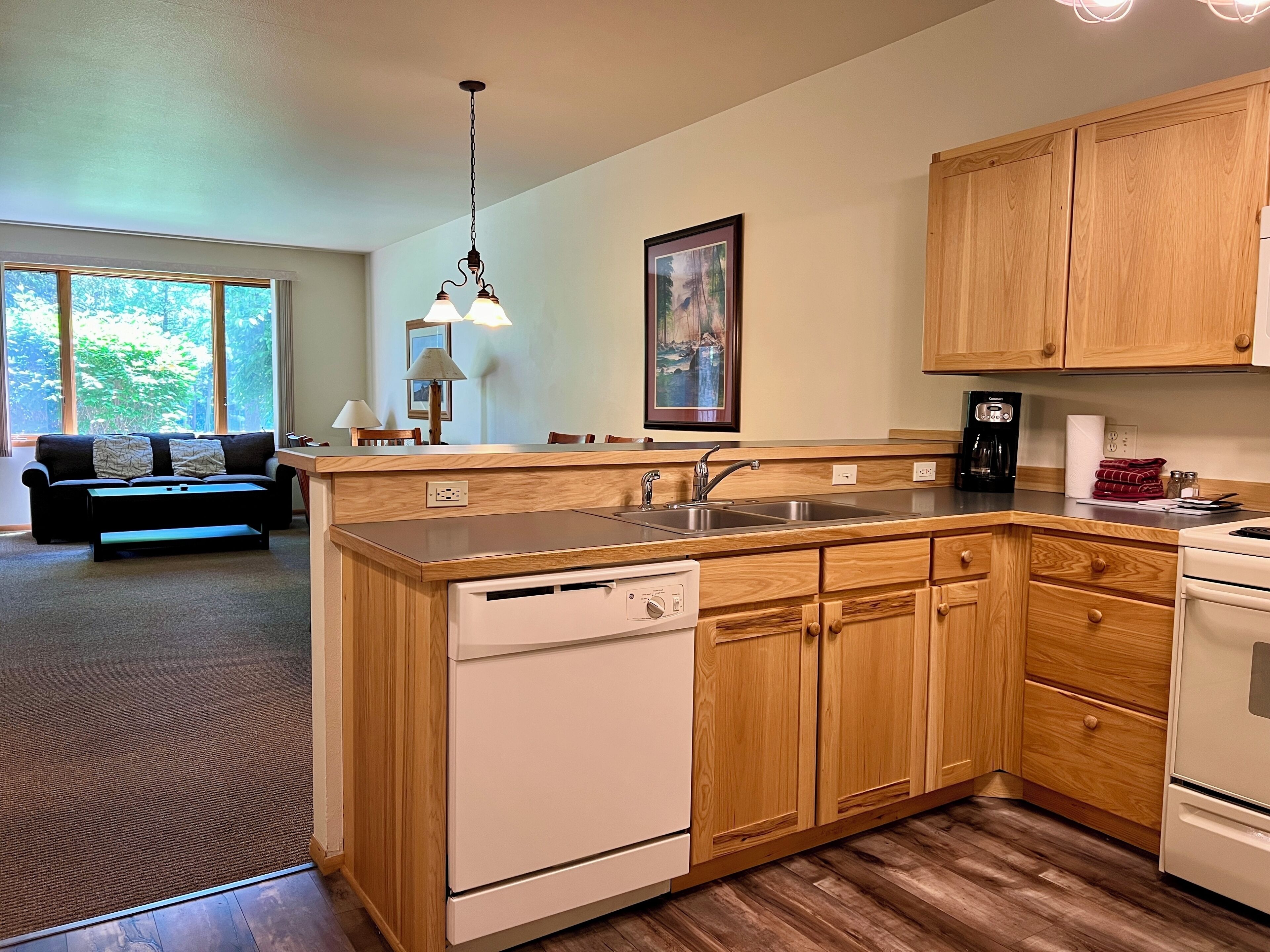 A modern kitchen with wooden cabinets, a built-in dishwasher, and a coffee maker.