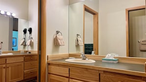 A hotel bathroom with wooden cabinets, a sink, a mirror with lights, and a towel rack. - Meadow Lake Private Timeshares (Columbia Falls)