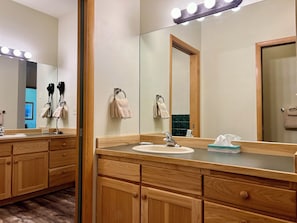 Ein Badezimmer in einem Hotel mit Holzschränken, einem Waschbecken, einem Spiegel mit Beleuchtung und einem Handtuchhalter.