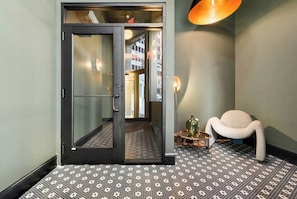 Eine Hotelhalle mit einem gemusterten Boden, einem modernen Sessel und einer Tür zu einem weiteren Raum.