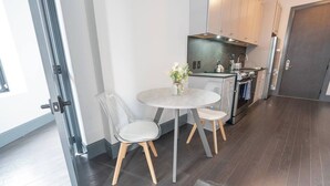 A modern kitchen with a round table and two chairs, a stove, and a refrigerator. - Urban 1BR Downtown–Close (Pittsburgh)