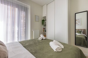 Ett hotellrum med en säng, en garderob, en spegel och ett fönster med gardiner.