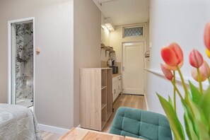 A narrow hallway leading to a kitchen with wooden cabinets and a white door. - Studio Dali | Old Bakery | Zandvoort Centre (Zandvoort)