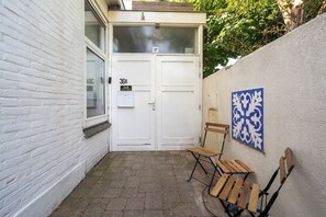 A white door with a number plate, a bench, and a wall-mounted decorative piece. - Studio Dali | Old Bakery | Zandvoort Centre (Zandvoort)