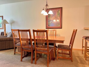 A dining area with a wooden table and chairs, a painting on the wall, and a lamp. - Meadow Lake Private Timeshares (Columbia Falls)