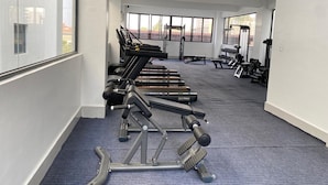 A gym with exercise equipment, large windows, and a carpeted floor.