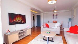 Una sala de estar moderna con televisor de pantalla plana, un sofá, una mesa de centro y una pintura de chimenea.