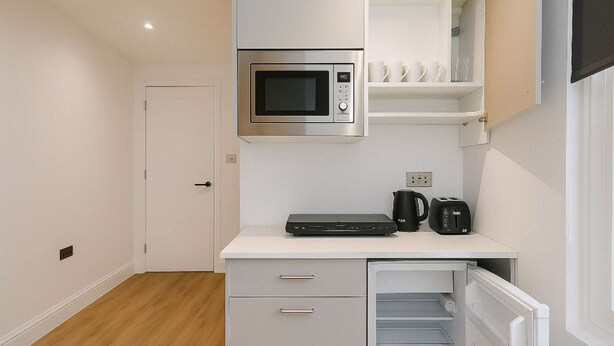 Eine kleine Küchenzeile mit einer Mikrowelle, einer Kaffeemaschine und einem Toaster auf der Arbeitsfläche.