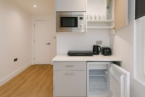 A compact kitchenette with a microwave, a coffee maker, and a toaster on the countertop. - Large Studio | Private Bathroom & Kitchenette NW10 (Greater London)
