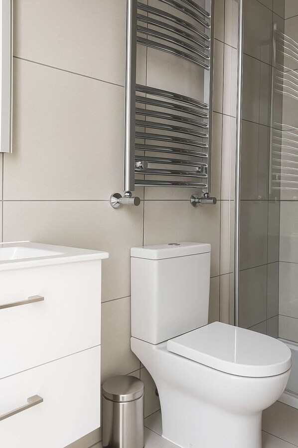 Ein modernes Badezimmer mit Toilette, Waschbecken und Duschbereich.