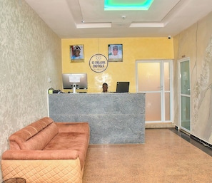 Una zona d'entrada amb una recepció, un ordinador i un sofà.