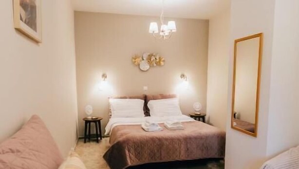 Ein Schlafzimmer mit zwei Betten, einem Schlafsofa, einer Chandelüster und einem Spiegel.