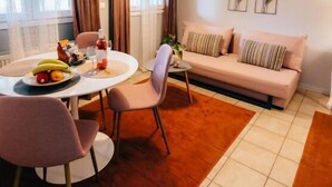 Ein modernes Wohnzimmer mit einer Couch, einem Esstisch mit Stühlen und einer Pendelleuchte.