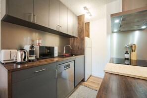 Eine moderne Küche mit grauen Schränken, einer Holz Arbeitsplatte, einem eingebauten Geschirrspüler, einer Mikrowelle, einem Toaster und einem Spülbecken.