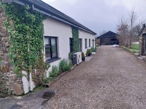 A gravel driveway leading to a building with a stone wall partially covered in ivy. - House Sleeps 11 With Parking (Tralee)