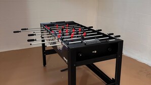 Een tafelvoetbaltafel in een kamer met witte muren en een raam.
