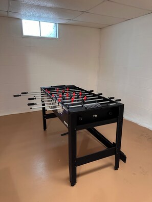 Ein Fußballtisch in einem Raum mit weißen Wänden und einem Fenster.