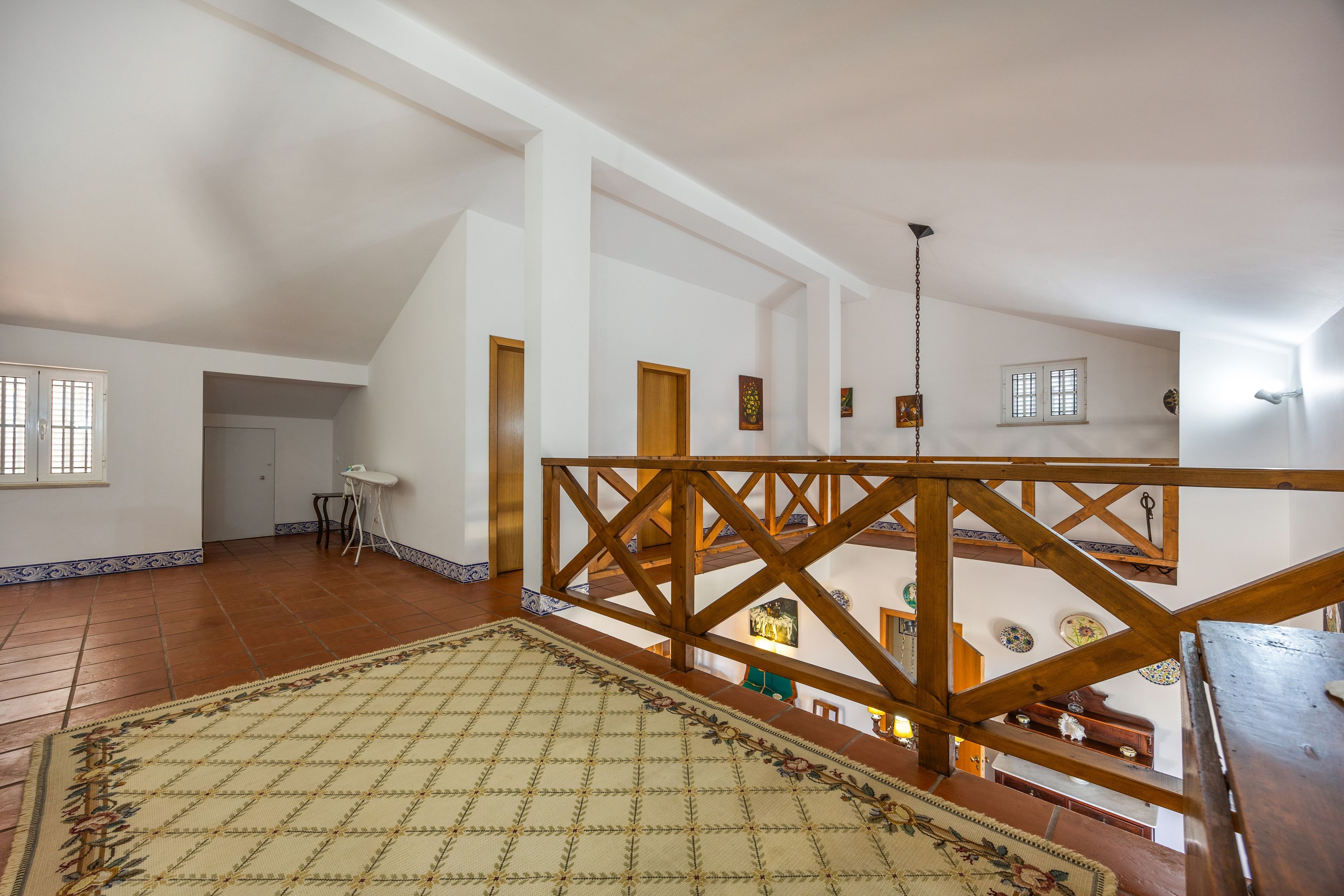 Une pièce spacieuse avec un plafond haut, un escalier en bois et une vue sur le niveau inférieur.