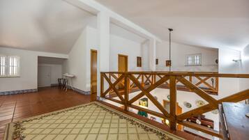 Une pièce spacieuse avec un plafond haut, un escalier en bois et une vue sur le niveau inférieur.