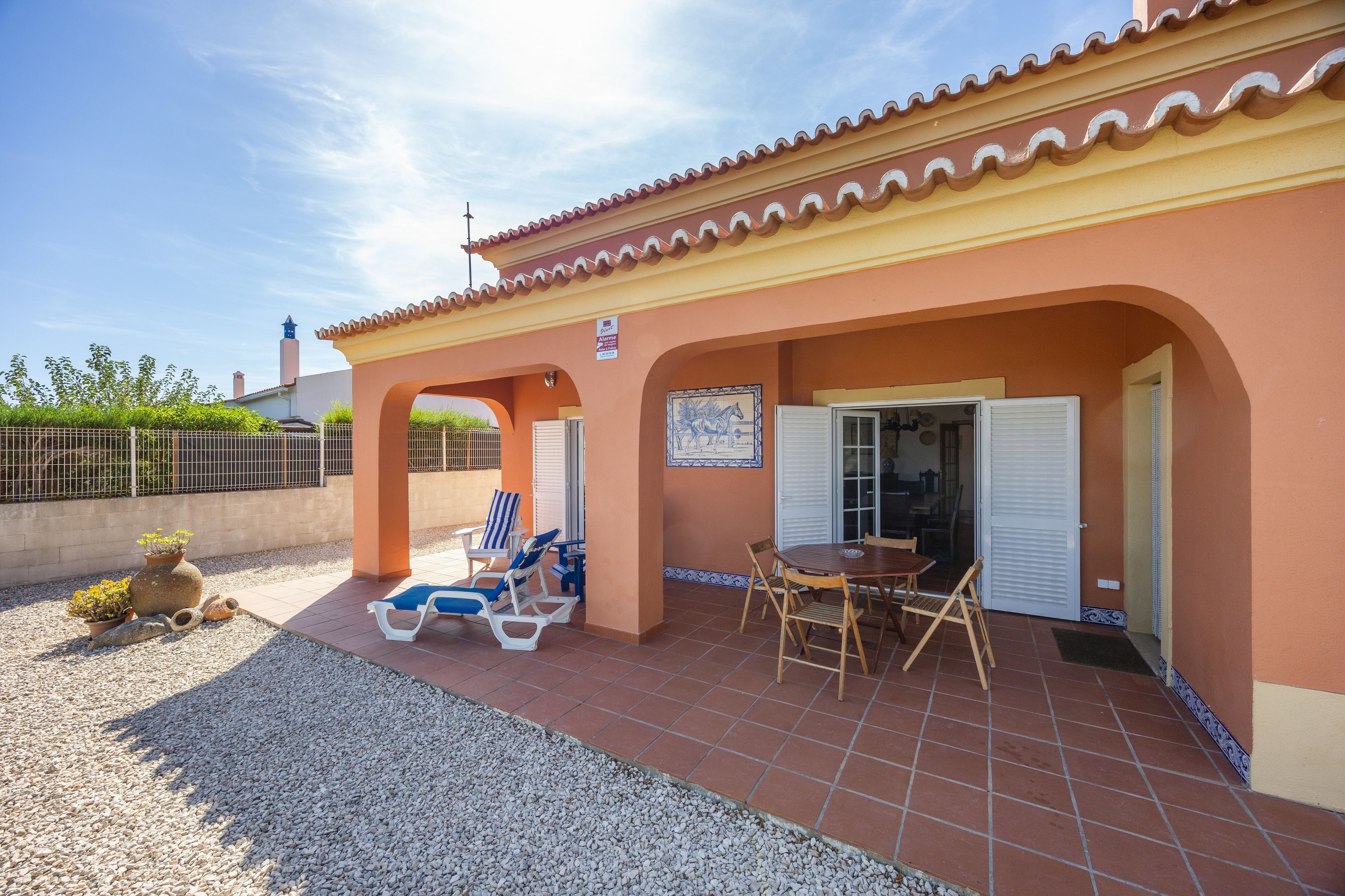 A building with a tiled patio, outdoor seating, and a view of the sky.