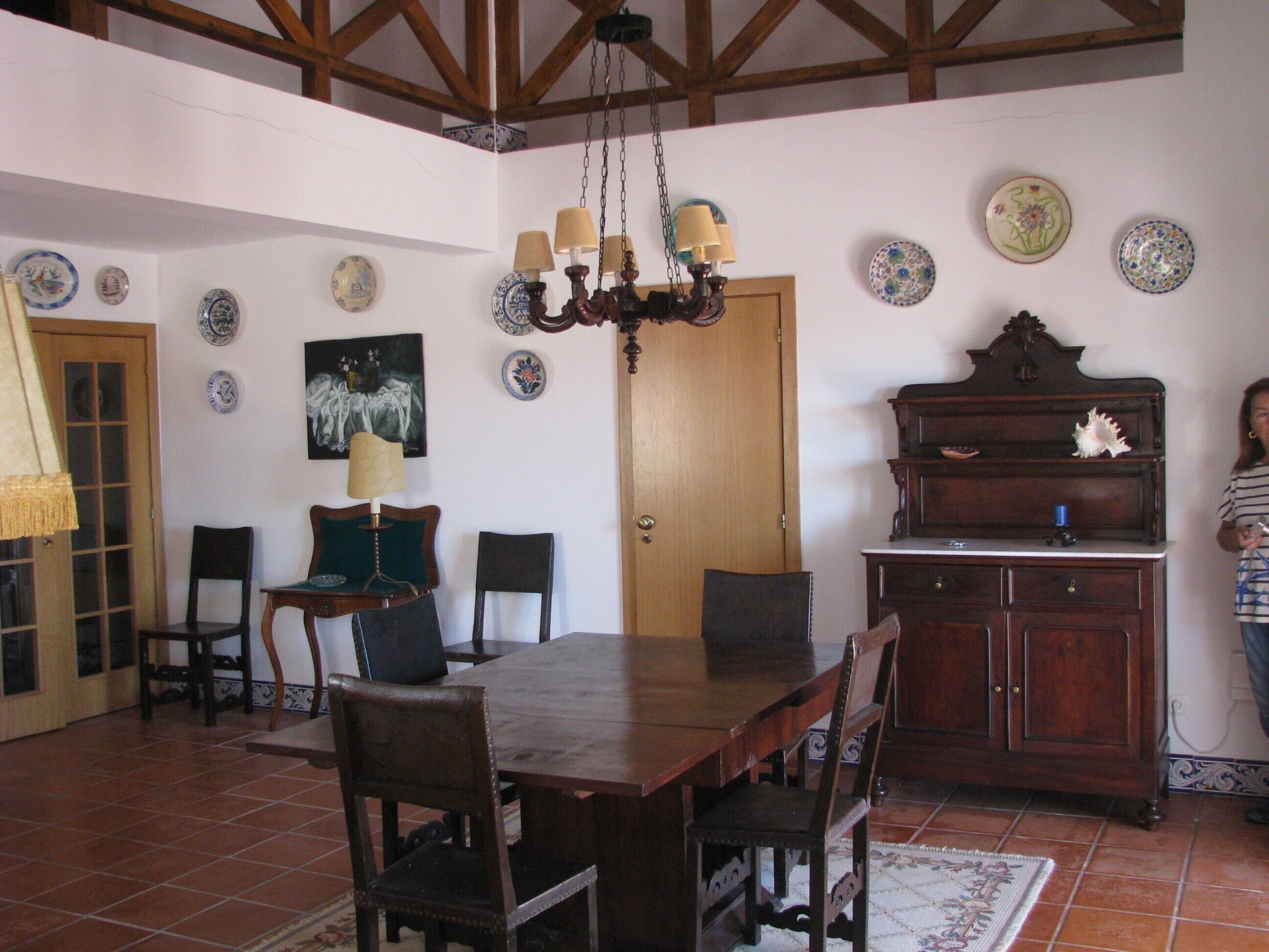 A dining room with a wooden table, chairs, a chandelier, and a piano.