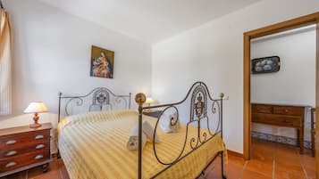 Une chambre à coucher avec un lit, une table de chevet, une commode, un tableau au mur et un miroir.
