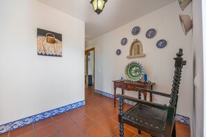 A hallway with a bench, a wall-mounted lamp, and decorative plates.