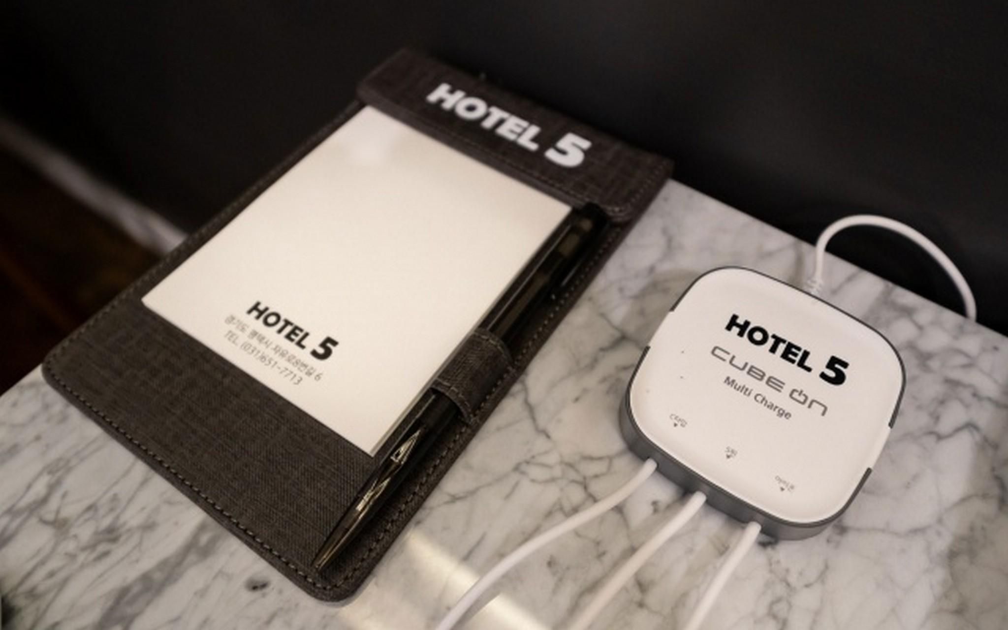 Una tarjeta de hotel y un cargador portátil etiquetado 'HOTEL 5' sobre una superficie de mármol.