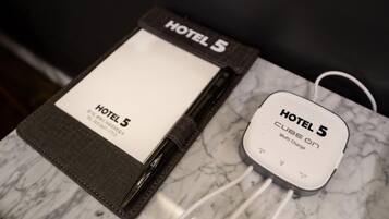 Una tarjeta de hotel y un cargador portátil etiquetado 'HOTEL 5' sobre una superficie de mármol.