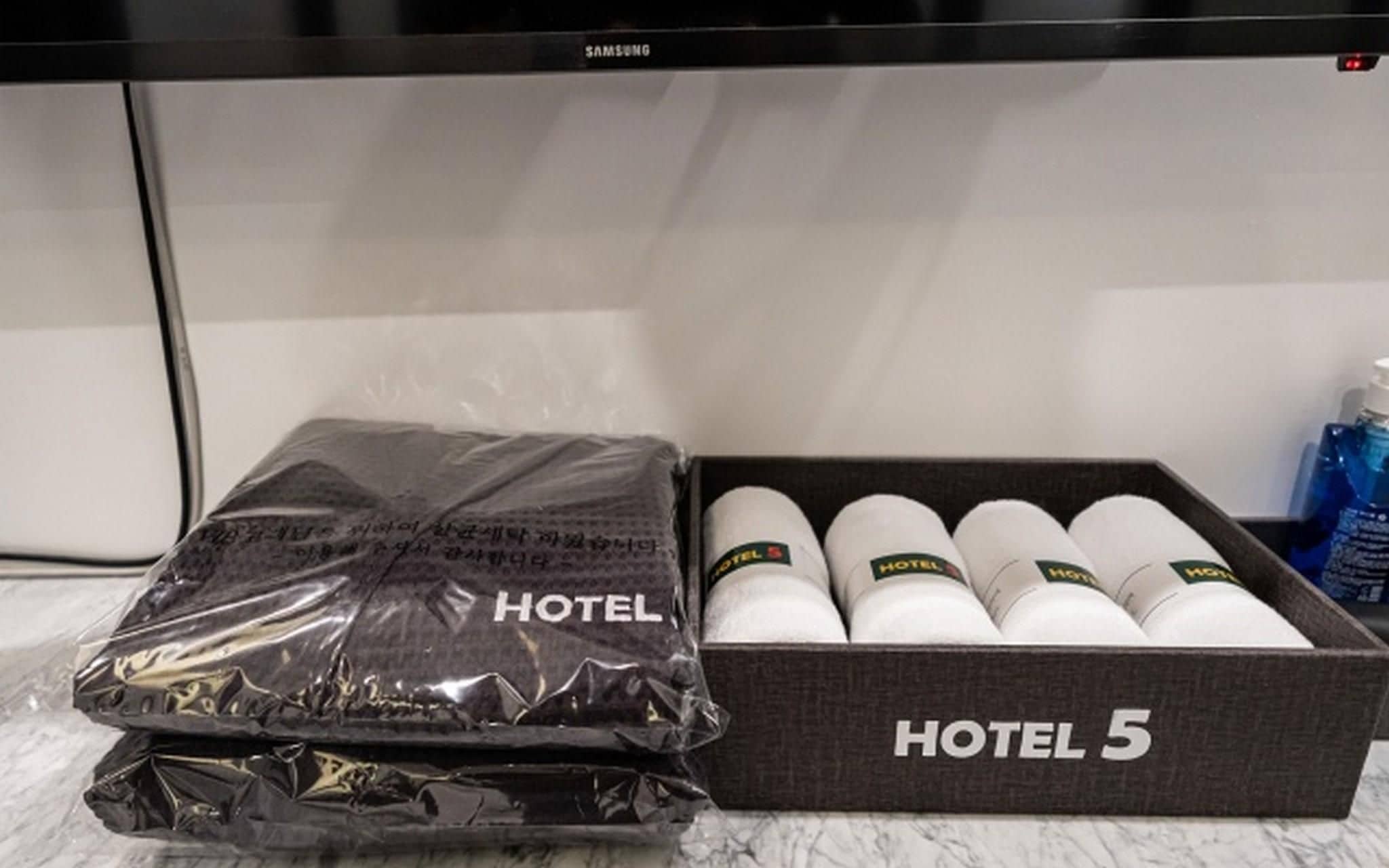 A black box labeled 'HOTEL 5' with white cylindrical containers and a black plastic bag with 'HOTEL' printed on it.