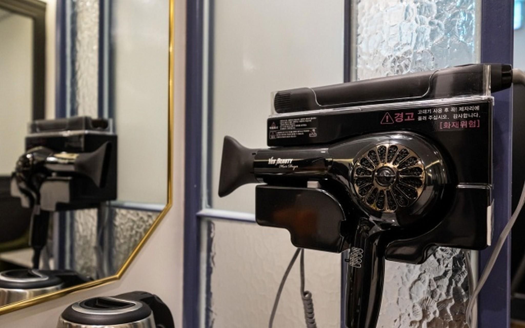 A hair dryer on a stand with a mirror reflecting its image.