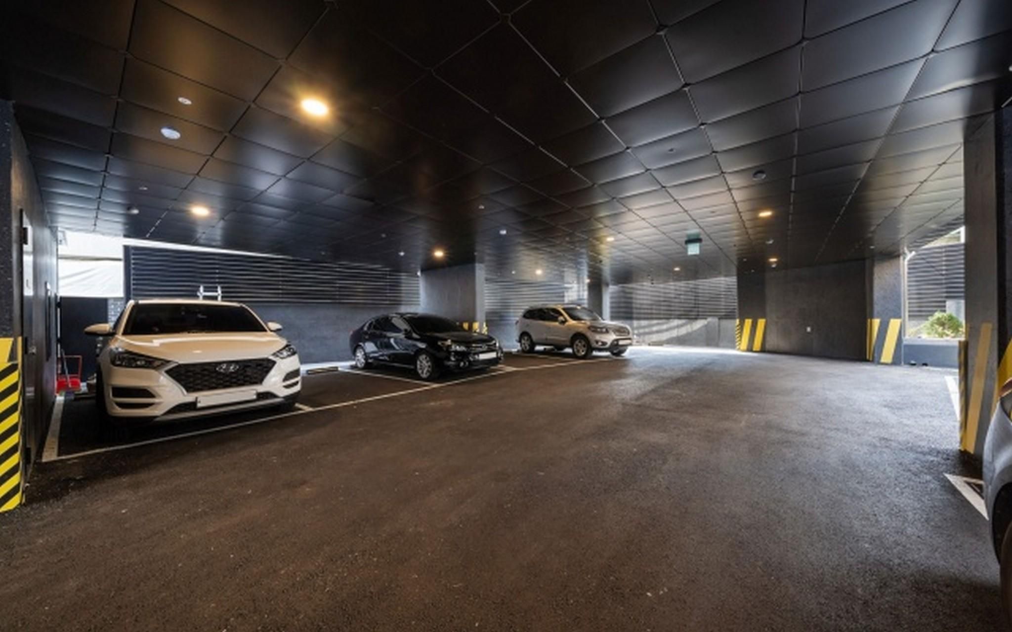 A covered parking garage with three cars parked in designated spaces.