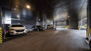 A covered parking garage with three cars parked in designated spaces.