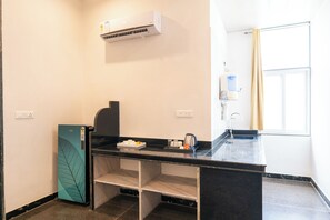 A modern kitchen with a black countertop, a built-in stove, and a water dispenser. - ELIVAAS Signature Hiara Karma 5BHK Villa (Udaipur)