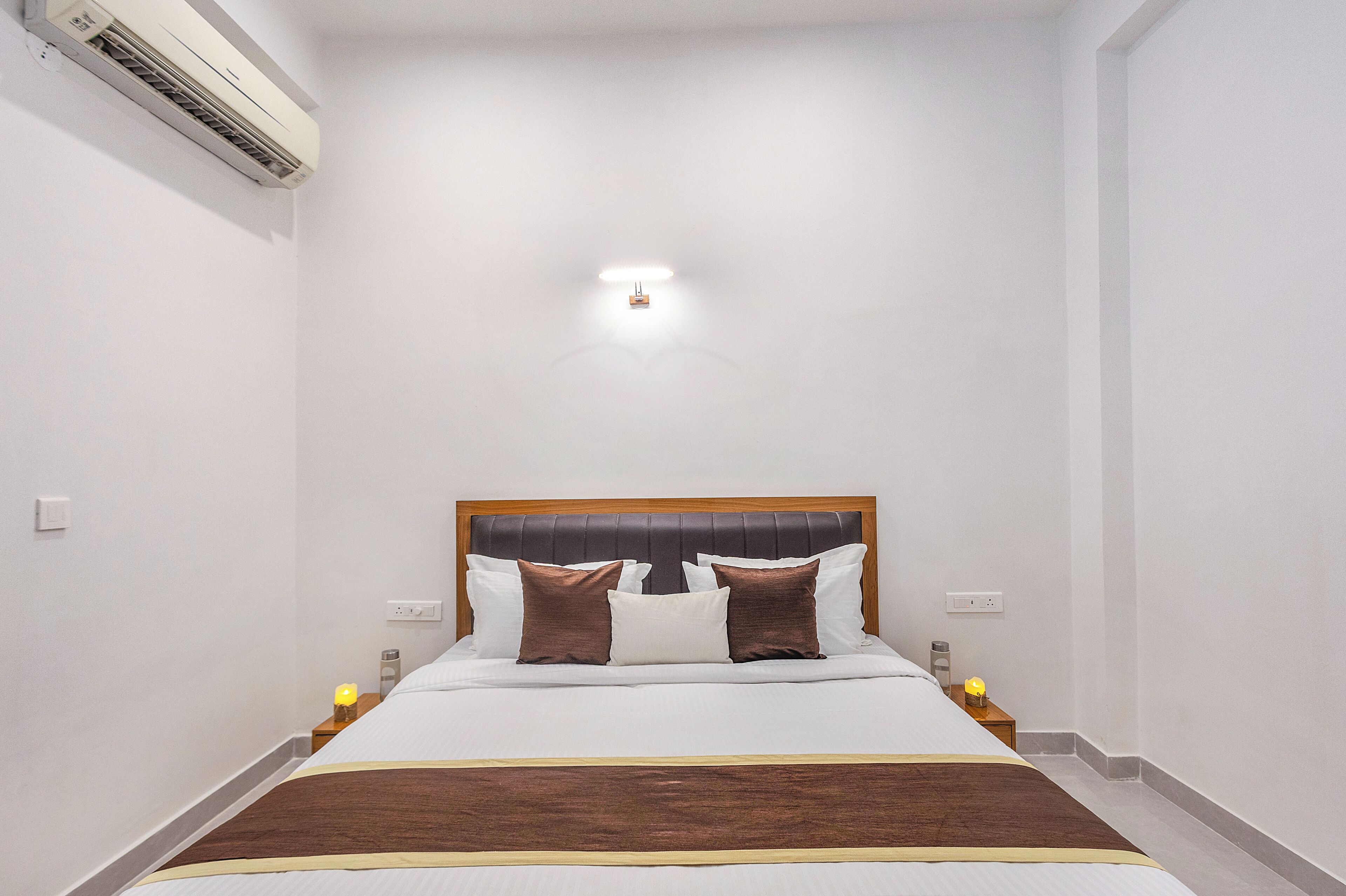 Une chambre d’hôtel équipée d’un lit, de lampes de chevet, d’un appareil de climatisation et d’un luminaire fixé au mur.