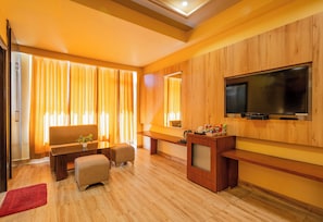 Una sala de estar moderna con una televisión de pantalla plana montada en la pared, un sofá, una mesa de centro y un pequeño reposapiés.