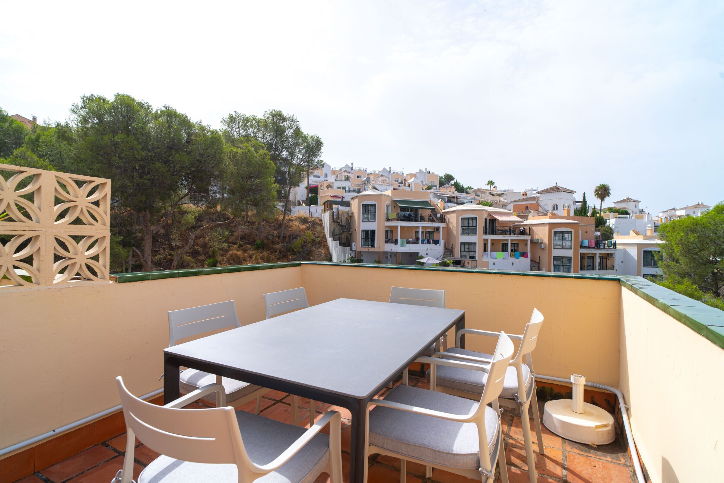 Una terraza con mesa y sillas, con vistas a una zona residencial con casas y vegetación.